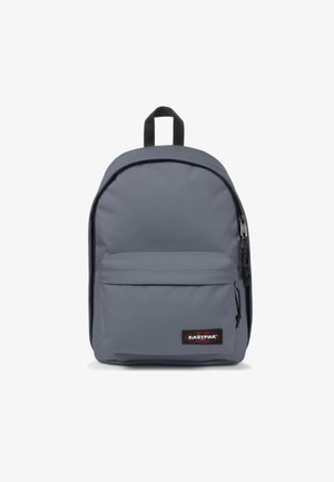Zaino grigio realizzato in tessuto resistente, dotato di un grande scomparto principale, tasca frontale con zip e maniglia superiore per il trasporto. Presenti dettagli neri.