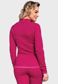 Enganliegendes Langarmoberteil und passende Unterteile in leuchtendem Pink, aus weichem Material gefertigt. Verfügt über einen runden Halsauschnitt und eine glatte Textur.