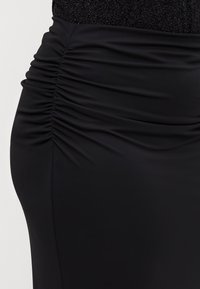 Svart kroppsnær skjørt med samlet detaljer på siden, laget av glatt, elastisk stoff med en tettsittende silhuett.