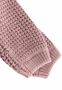 Primo piano delle maniche di un morbido maglione rosa lavorato a maglia con polsini a coste e motivo a punto testurizzato su sfondo bianco.