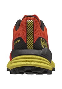 Červená a černá běžecká bota s pružným materiálem, žlutou podrážkou a výrazným pruhovaným akcentem na patě. Texturovaná podešev pro lepší přilnavost.