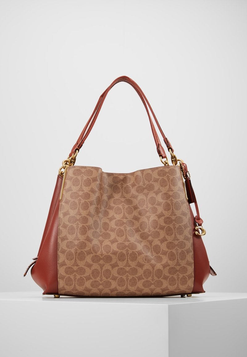 Sac à main marron clair avec un motif circulaire, accents en cuir marron, garnitures dorées et deux anses marron. Design structuré et spacieux.