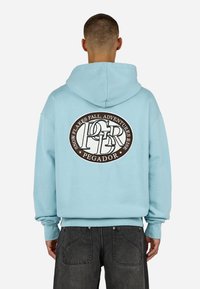 Γαλάζια Hoodie με μεγάλο κυκλικό καφέ κεντητό λογότυπο στο πίσω μέρος, το οποίο περιλαμβάνει κείμενο. Διαθέτει ευρύχωρη κουκούλα και πλισέ μανσέτες.