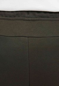 Leggings de verde oliva oscuro con una textura suave y elástica, cintura elástica y detalles de costuras reforzadas para mayor durabilidad.