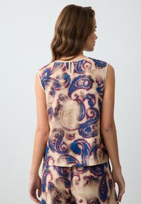 Ärmelloses Top mit einem Paisleymuster in Blau, Lila und Creme, mit einer Schlüssel-Öffnung mit Knopfverschluss auf der Rückseite und einem weichen, strukturierten Stoff.