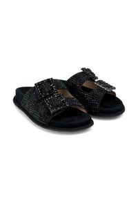 Sandales à glissière noires avec doubles boucles, ornées de clous noirs et de brides en suede doux. Semelle plate, design ouvert au niveau des orteils et style minimaliste.