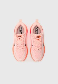 Light pink athletic shoes with a mesh upper, black accents, and orange sole. Features laces and a padded collar for comfort.