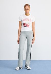 T-shirt blanc avec un graphic rouge "JORDAN" et une illustration de basket-ball, associé à un pantalon de survêtement gris avec des bandes latérales noires et le logo Nike.