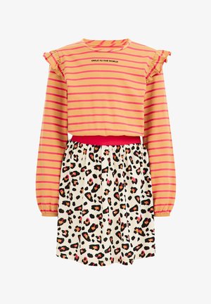 Pomarańczowo-różowa bluzka w paski z długim rękawem i falbanami na ramionach oraz napisem „SMILE TO THE WORLD”, zestawiona z białą spódnicą w cętki pantery.