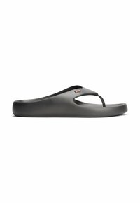 Czerną gumową klapkę typu flip-flop z grubą podeszwą i małą odznaką logo w kolorze czerwono-białym na górnym pasku.