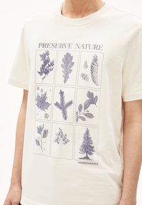 Korte mouwen crème t-shirt met een botanische print met negen plantillustraties in het blauw, gelabeld "Preserve Nature", van zacht katoen.