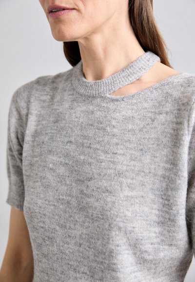 Pull en tricot gris clair à manches courtes avec un détail découpé unique au niveau du cou. Texture douce, col côtelé et design minimaliste.
