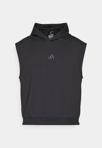 Juodas be rankovių džemperis su gobtuvu, pagamintas iš minkštos medžiagos, su priekyje esančia kengūros kišene ir mažesniu atspindinčiu prekės ženklo logotipu ant krūtinės.