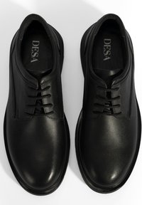 Zwarte leren veterschoenen met een gladde afwerking, ronde neus en subtiele stikdetails. Het interieur heeft een gevoerd voetbed.