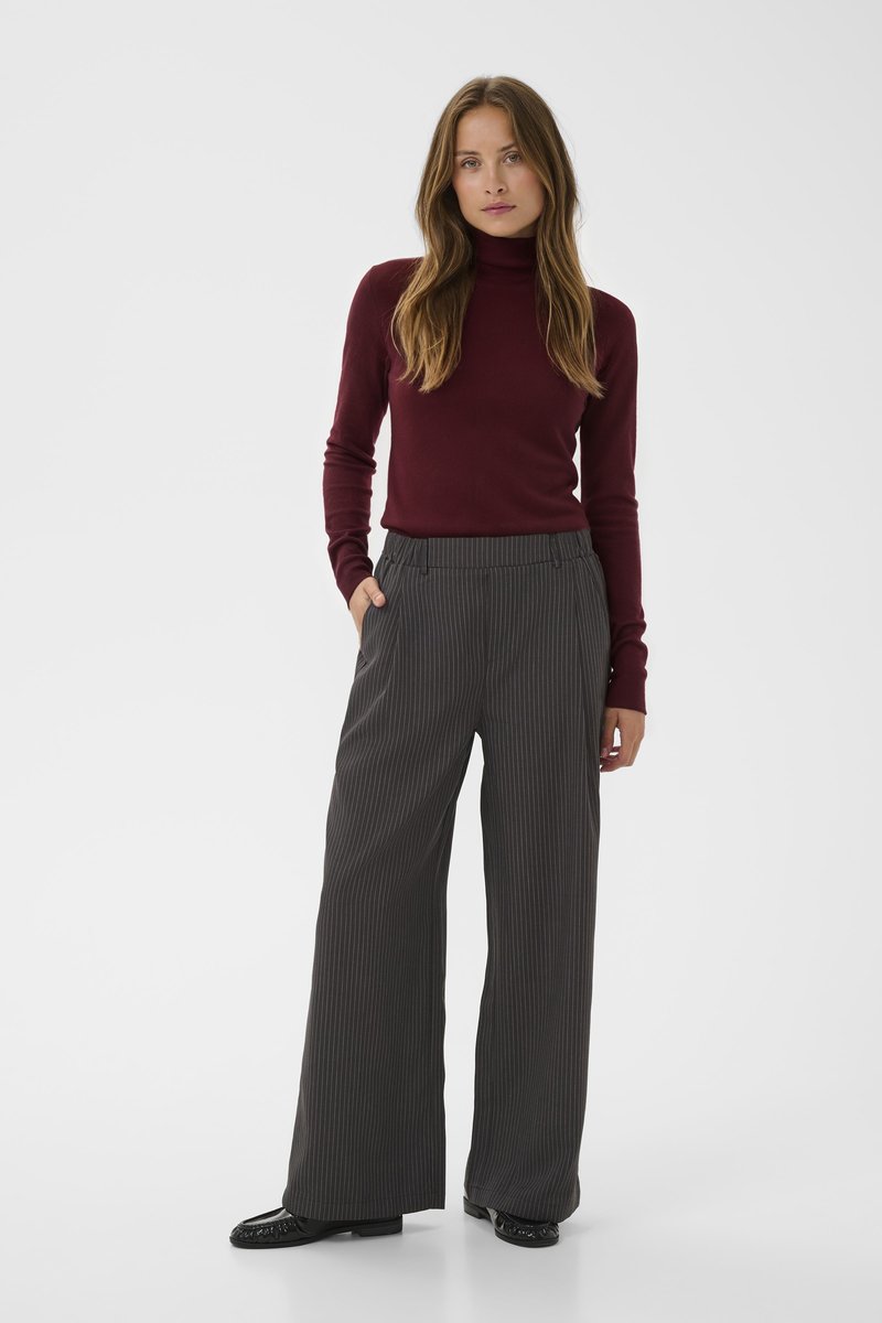 Suéter de cuello alto burdeos combinado con pantalones de pinza grises de pierna ancha y cintura alta, con bolsillos frontales y un corte relajado.