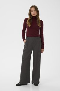 Pull à col roulé bordeaux associé à un pantalon gris à rayures tailleur taille haute et ample, avec des poches avant et une coupe décontractée.