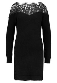 Robe tricotée noire avec un empiècement en dentelle au niveau du col, à manches longues et avec une texture côtelée subtile. Longueur mi-cuisse.