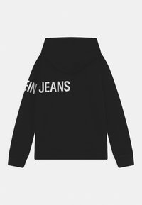 Felpa nera con cappuccio caratterizzata da una grande stampa di testo bianco che recita "JEANS" sul retro. Il materiale sembra morbido, con una vestibilità rilassata e una tasca a marsupio.