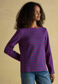 Pikkade varrukatega triibuline topp, millel on tumesinine alus roosade horisontaalsete triipudega, ümar kaelus ja lõdvenenud lõige. Pehme kangastekstuuri.