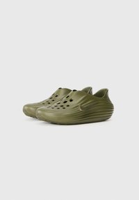 Vihreät kumisaappaat, joissa on sileä pinta, pyöreä muoto, useita tuuletusaukkoja ja sivussa Nike-logon korostus.