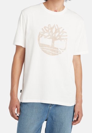 Valkoinen puuvillainen t-paita, jossa keskellä vaaleanruskea puun logo. Paidassa on lyhyet hihat ja pyöreä pääntie, ja se on malliltaan rento.
