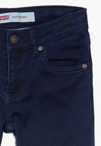 Vaqueros ajustados Levi's 510 en azul oscuro con un diseño elegante, que cuenta con detalles en botón de metal, un bolsillo frontal y una textura de denim suave.