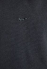 Felpa nera Nike con logo ricamato discreto, texture in cotone morbido e colletto tondo semplice.