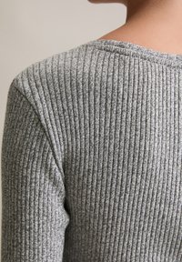 Gray ribbed knit top with a round neckline, featuring a textured fabric and fitted silhouette, showcasing fine horizontal lines.