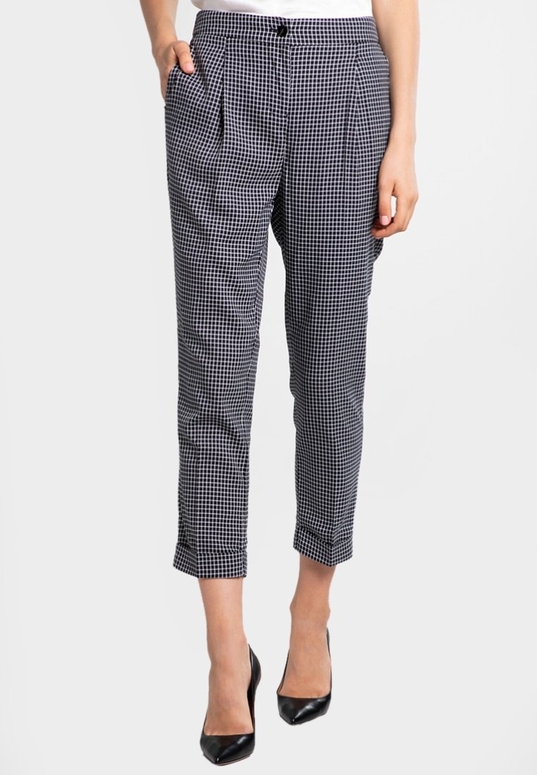 Black and white gingham check pants with pleats, tapered legs, and side pockets. Fastened with a button at the waist.