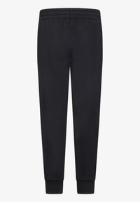 Čierne tepláky vyrobené z mäkkej látky, s elastickým pásom a rebrovanými manžetami pre priliehavý vzhľad. Hladká textúra, bez vzorov.