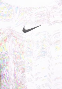 Bílý tričko s barevným vlnitým vzorem a malým černým logem Nike na levé horní straně. Měkká, strukturovaná tkanina.