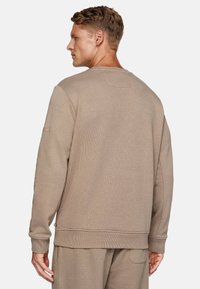 Beige crew neck sweatshirt with ribbed cuffs and hem. Soft texture with minimal stitching details. Adjustable features at the waist.