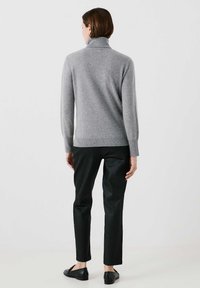 Grå, lätt turtleneck-tröja gjord av mjukt material, kombinerad med svarta skräddarsydda byxor och svarta skor, utan mönster eller utsmyckningar.