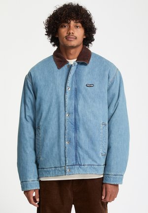 Lyseblå denimjakke med en brun ribstopkrave, trykknaplukning og sidelommer; har et lille logo på brystet.