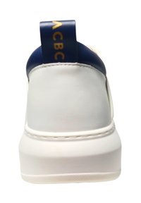 Baskets blanches avec une surface texturée, talon bleu marine et lettres dorées sur l'onglet du talon. Présente une semelle épaisse blanche pour la stabilité.