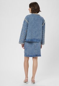 Denim jacket and skirt set, featuring quilted diamond pattern, pearl accents on sleeves and hem, in medium blue color.