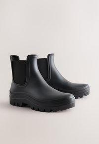 Pair of black rubber ankle rain boots with elastic side panels and thick treaded soles on a plain light background.