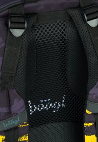 Imbottitura in rete nera con perforazioni esagonali, con logo. Tessuto viola adiacente con motivi astratti e accenti gialli.