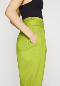 Hoge taille, fel limoen groene broek met een riem en zak, met een gladde textuur en een op maat gemaakte pasvorm.