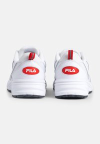 Scarpe sportive bianche con accenti rossi. Il design presenta un colletto imbottito, tomaia in mesh testurizzato e un logo FILA prominente sul tallone.