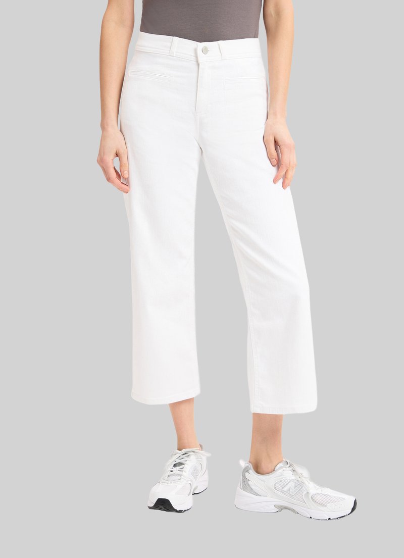 Weiße, verkürzte Jeanshose mit geradem Bein. Sie verfügt über einen vorderen Knopfverschluss, Seitentaschen und eine glatte Textur. Kombiniert mit einem grauen Oberteil und Turnschuhen.