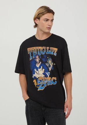T-shirt oversized nera con una vivace stampa grafica di 2Pac, accompagnata dalla scritta "THUG LIFE" in lettere colorate. Tessuto in cotone, vestibilità casual.