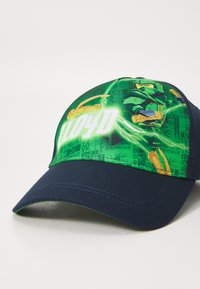 Gorra de béisbol verde con un gráfico de un personaje con una espada. La visera es azul marino y el material parece ser algodón.