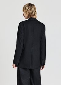 Giacca di abito nera a righe sottili realizzata in tessuto liscio. Presenta un colletto classico, una vestibilità su misura e un design minimalista con maniche lunghe.