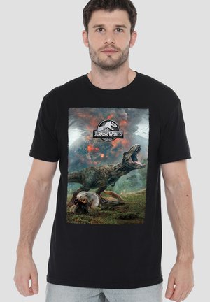 Mann trägt ein schwarzes T-Shirt mit Jurassic World-Logo und einem Bild eines brüllenden T-Rex und zwei Personen, die sich hinter einem umgestürzten Fahrzeug verstecken.