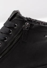 Sort læder ankelstøvle med tekstureret grå foring, der har sorte snørebånd, sølvfarvet hardware og en sidelukning for nem adgang.