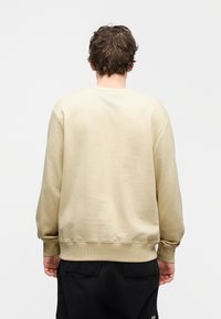 Μπεζ βαμβακερό φούτερ με μακριά μ ανίκια, ριμπ μανσέτες και τελείωμα, και στρογγυλή λαιμόκοψη. Ομαλή υφή με απλό σχέδιο, χωρίς γραφικά ή σχέδια.