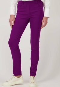 Paasvormige paarse stretchbroek met zakken, gecombineerd met witte sneakers. Gladde textuur en een op maat gemaakt ontwerp voor een gestroomlijnde uitstraling.