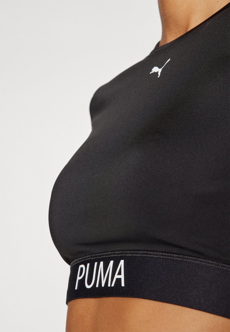Reggiseno sportivo nero realizzato in tessuto liscio, con il logo Puma bianco sul petto e una fascia nera a contrasto con il nome del marchio.