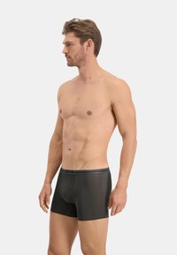 Boxer-briefs noirs au toucher lisse, avec une coupe ajustée et une ceinture sombre contrastante portant la mention "Levi's."